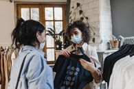 疫情期间，两名妇女戴着口罩在一家商店购买衣服