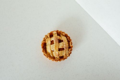 Free Top view of a single freshly baked mini pie on a light surface, showing lattice crust detailing. Stock Photo