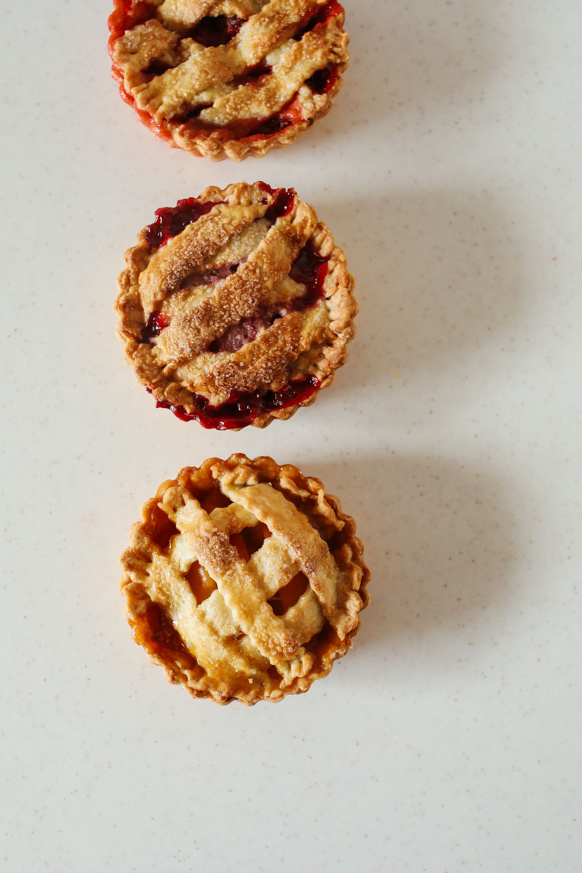 Top view of three cherry pies with golden lattice crust on a white background.