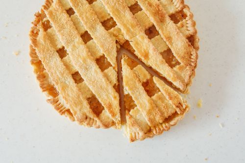 Free Top view of a freshly baked sliced apple pie with lattice crust on a white background. Stock Photo