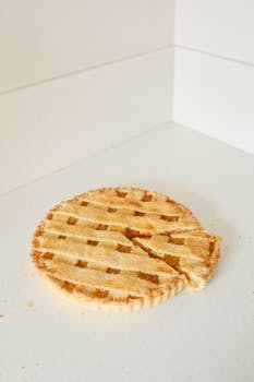 Close-up of a homemade lemon pie with a slice cut out on a clean white surface.