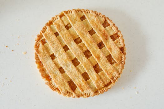 A close-up of a lattice-topped lemon pie on a light background, shot from above.