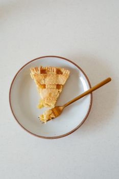 顶视图下，一个美味的柠檬馅饼片放在带有金叉子的碟子上，非常适合食物摄影