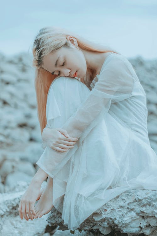 Free Calm woman with closed eyes sitting on rocks Stock Photo