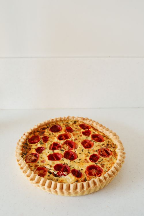 Free A savory tomato pie with golden crust against a clean, minimalist backdrop. Stock Photo