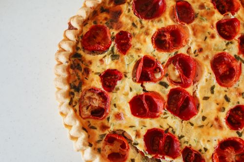 Free A mouthwatering overhead shot of a freshly baked tomato quiche garnished with herbs. Stock Photo