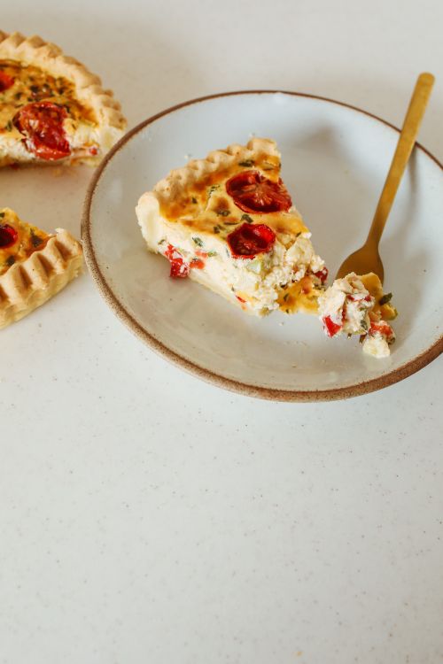 Free Tempting slice of tomato pie with a golden fork on a light plate, perfect for food styling. Stock Photo