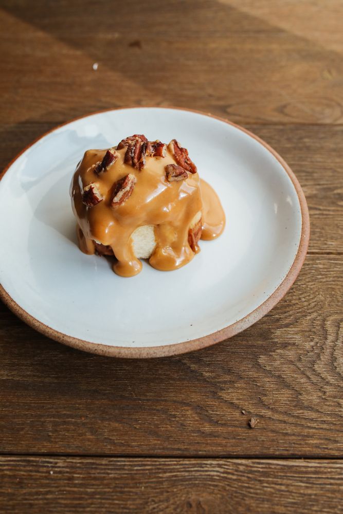 Individual sticky toffee pudding covered in thick golden toffee sauce and topped with chopped toasted pecans