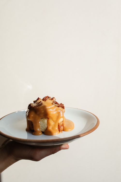 Free Close-up of a caramel-drizzled cinnamon bun on a plate, perfect for food enthusiasts. Stock Photo