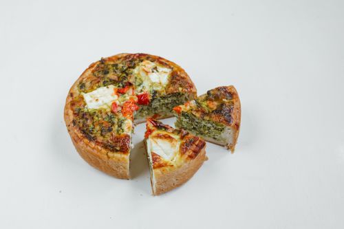 Free Delicious spinach and cheese quiche with cherry tomatoes on a white background, perfect for any meal. Stock Photo