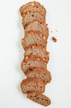 Sliced homemade banana walnut bread arranged vertically on a white background, showcasing its texture and delicious appeal.