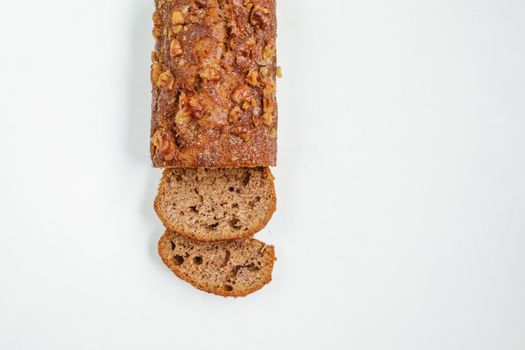 Close-up of freshly baked banana bread with walnuts, shot top view on white background.