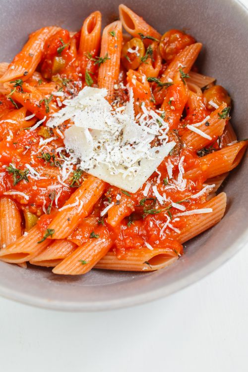 Free Close-up of penne pasta in rich tomato sauce topped with cheese, perfect for an Italian meal. Stock Photo