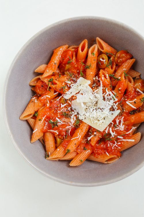 Free Close-up of penne pasta in red tomato sauce topped with cheese, showcasing classic Italian cuisine. Stock Photo