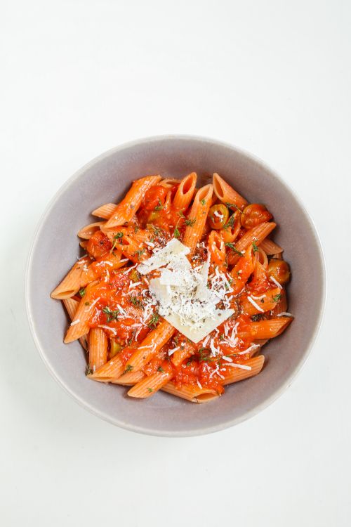 Free Top view of a white bowl filled with penne pasta in red sauce and cheese. Perfect for food photography. Stock Photo