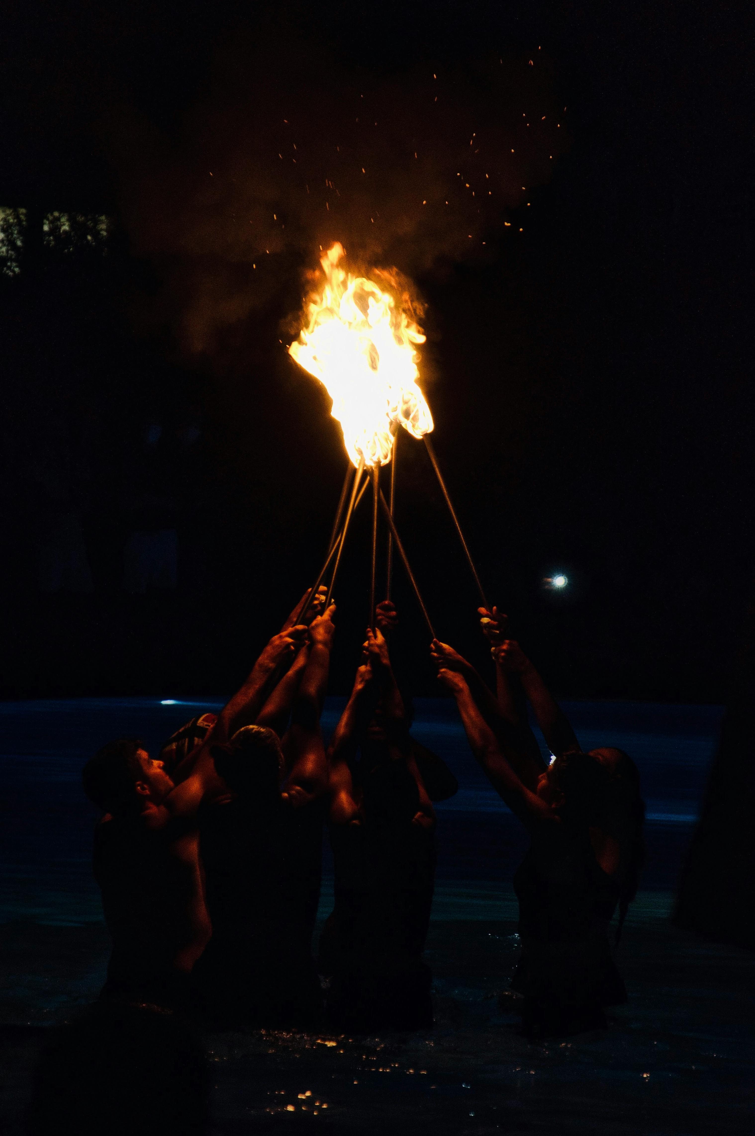 anonymous shirtless men with burning torches during performance in evening