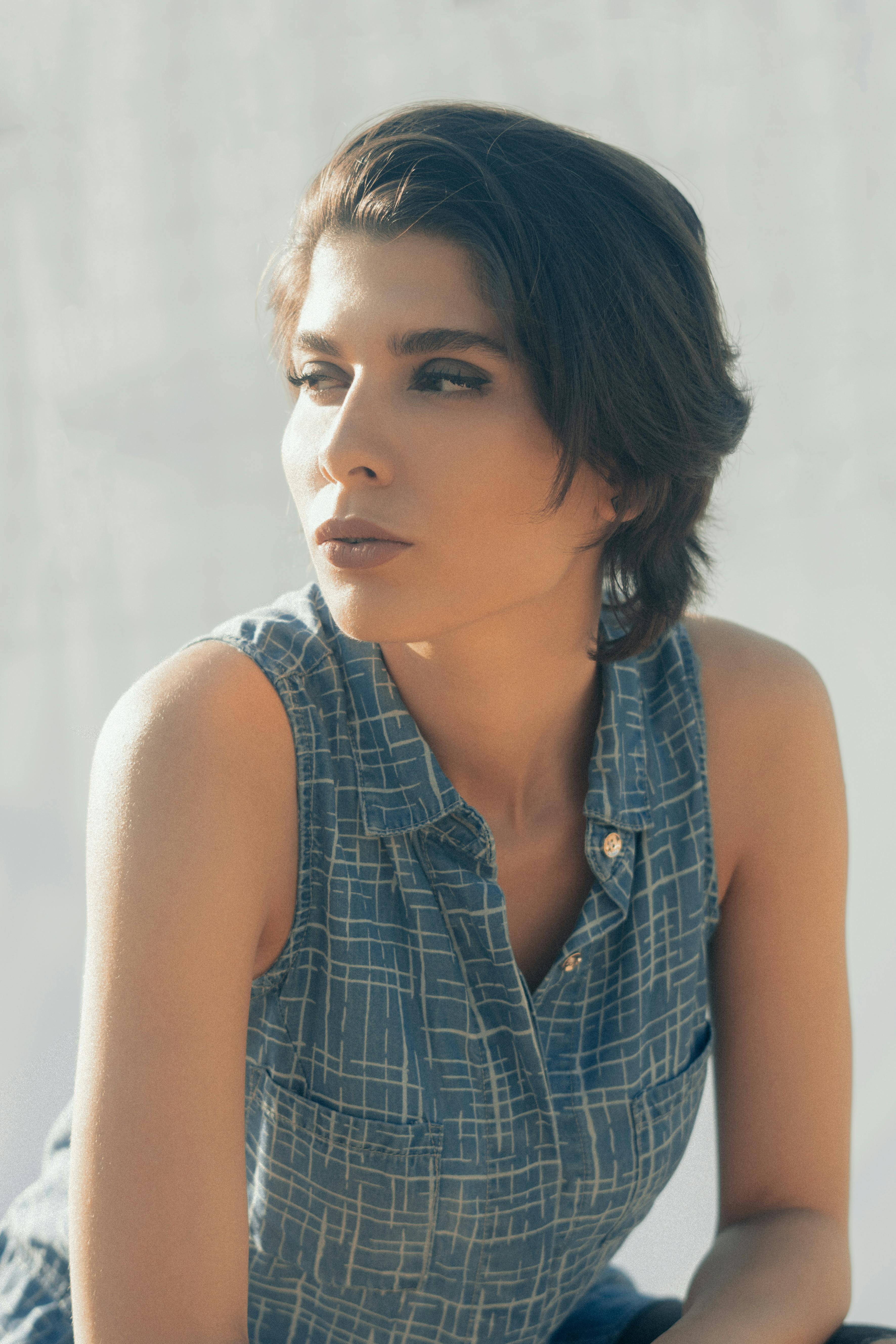 Pensive calm relaxed female with short hair looking away and pondering on gray background