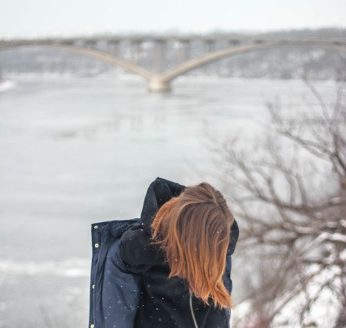 Free A woman walking in winter by a frozen river and bridge, capturing solitude and cold weather. Stock Photo