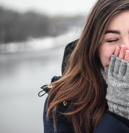 Femme En Doudoune à Capuche Noire Couvrant Son Visage Avec Des Gants Sans Doigts Gris