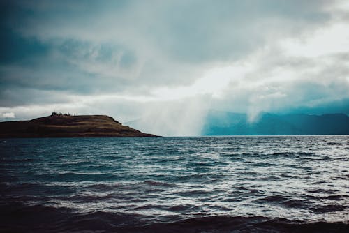 Cumulus clouds floating over rippling water with cliffs and grassy hills on nasty day