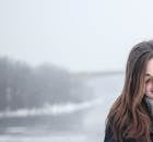 一名女子在白雪皑皑的河岸边，享受着宁静的冬日时光