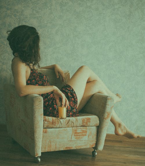 Free Unrecognizable woman relaxing on armchair with glass of juice Stock Photo