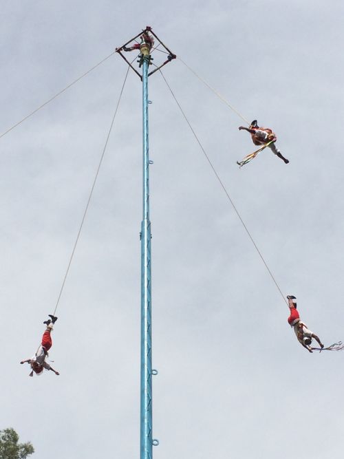 Free A captivating view of Mexican Voladores performing their traditional dance on a tall pole under a cloudy sky. Stock Photo