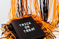 万圣节节日的标志上印有“不给糖就捣蛋”，周围环绕着橙色和黑色的丝带
