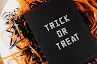 “不给糖就捣蛋”标志的特写，周围环绕着喜庆的橙色和黑色装饰彩带，非常适合用作万圣节装饰