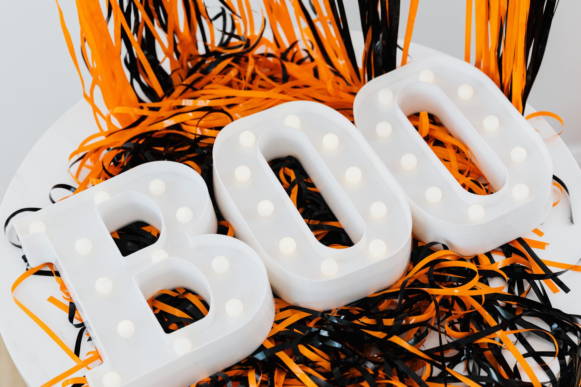 White Plastic Boo Signage on Orange and Black Plastic Tinsel