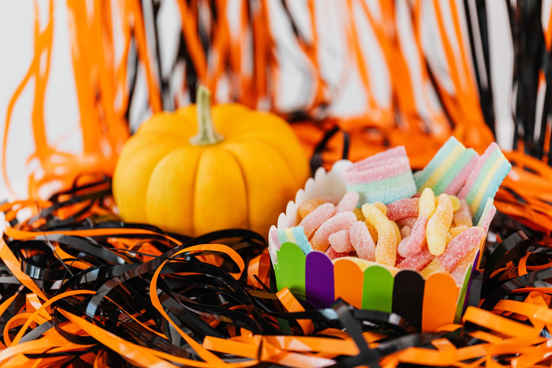 Assorted Chewy Candies in a Container Beside a Pumpkin