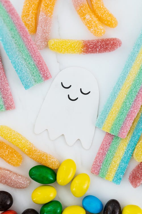 Free Lots of Candies Scattered Around a Cute Ghost Paper Cutout Stock Photo