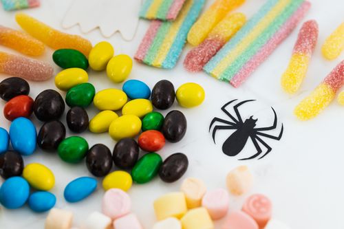 Free A vibrant assortment of candies with a playful toy spider layout on a white background. Stock Photo