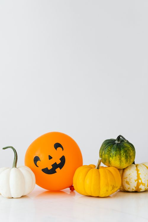 Free Colorful pumpkins and Jack-o'-Lantern balloon on white background, perfect for Halloween themes. Stock Photo