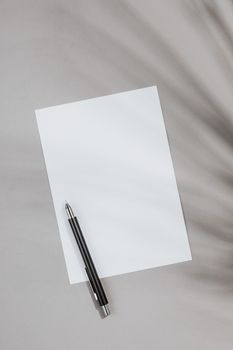 灰色背景上的一张白纸和一支笔，非常适合做笔记或画草图