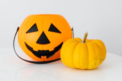 Free Bright Halloween decorations featuring a Jack-o'-lantern bucket and small pumpkin on a white background. Stock Photo