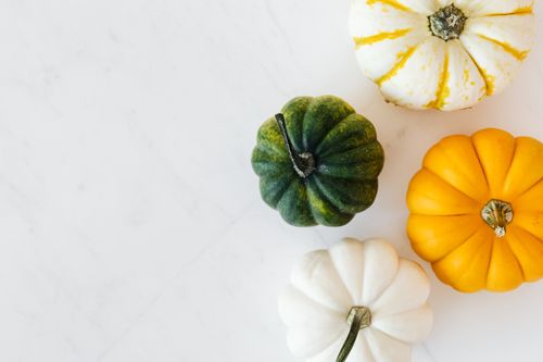 Free Top view of colorful mini pumpkins on a white marble background, perfect for autumn themes. Stock Photo