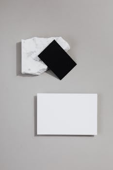 Elegant mockup of black and white business cards on marble and grey background.