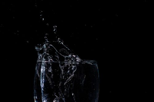 Free A close-up shot of water splashing in a glass against a black background, capturing movement. Stock Photo
