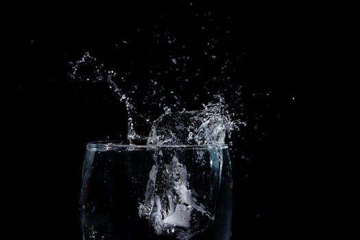 High-speed capture of water splashing out of a glass against a black backdrop, showcasing liquid motion.