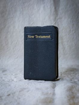 经典《新约圣经》以柔软的纹理背景垂直呈现，象征着信仰和灵性