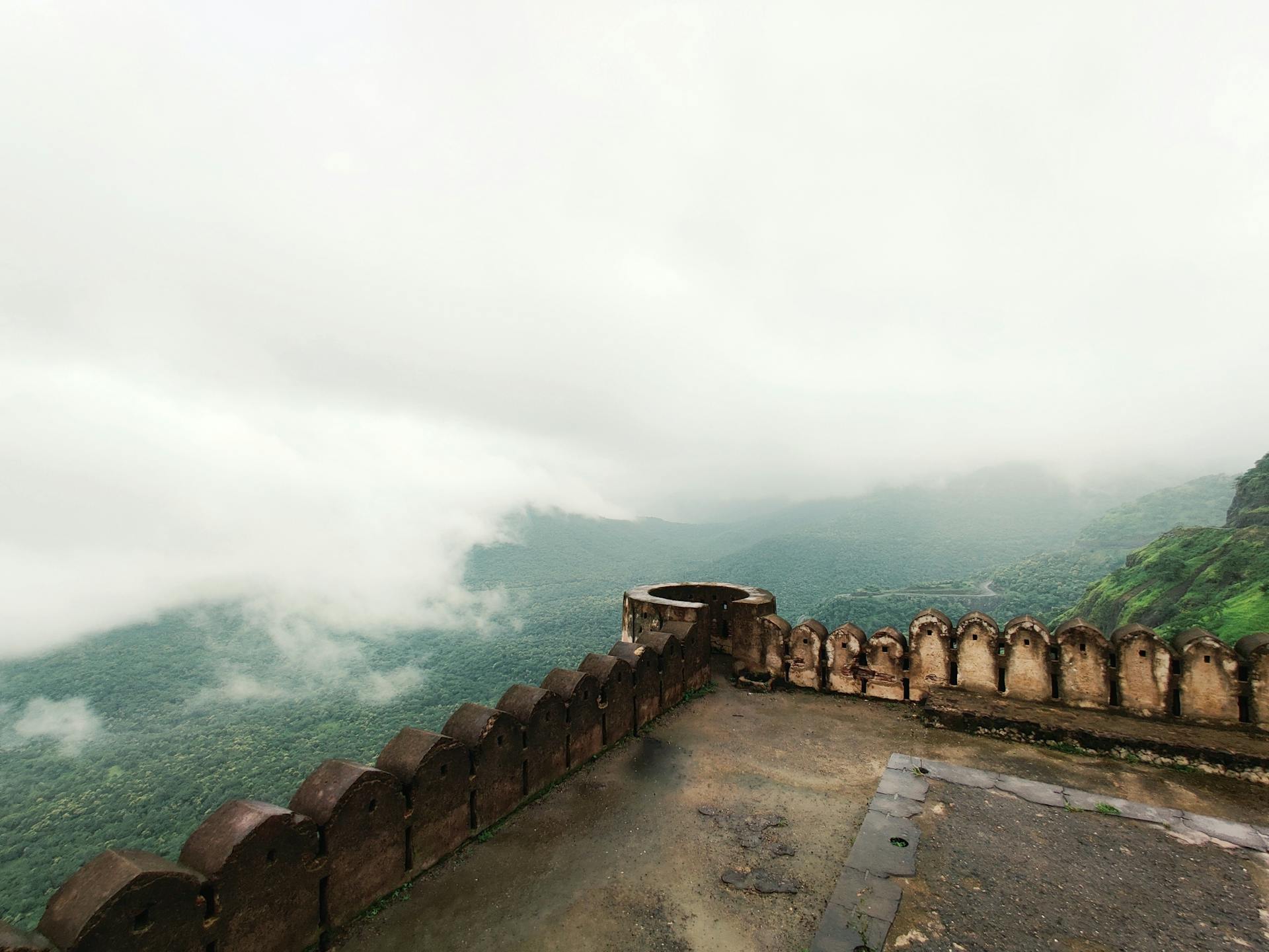 Explore a stunning foggy mountain landscape from an ancient stone fort. Perfect for travel and history enthusiasts.
