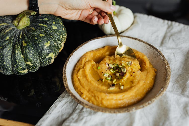 Hand Holding Spoon In Bowl With Food