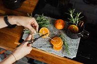 Hands Cutting Vegetables over Orange Slices