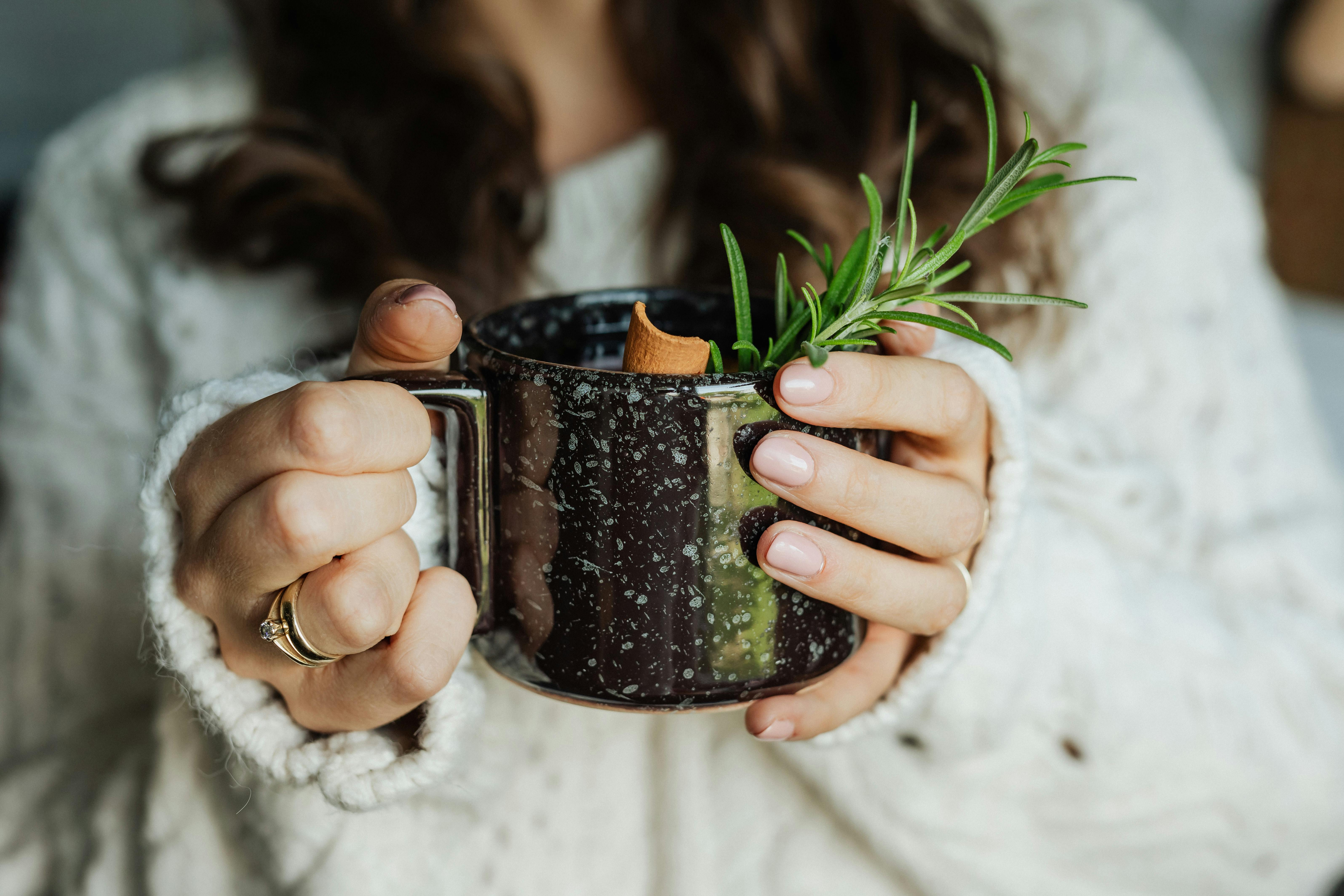 woman holding a cup of tea with herbs