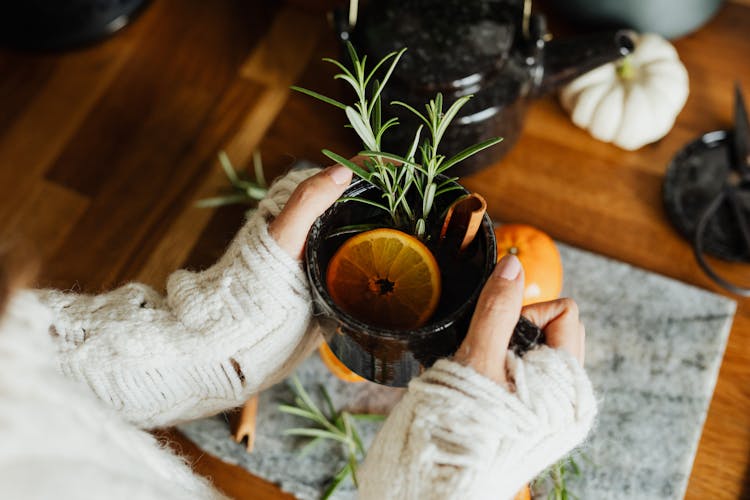 Woman Holding A Cup Of Tea With A Lemon Slice And Herbs 