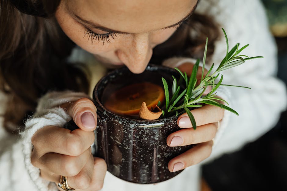 A steaming cup of rosemary tea with fresh rosemary sprigs beside it