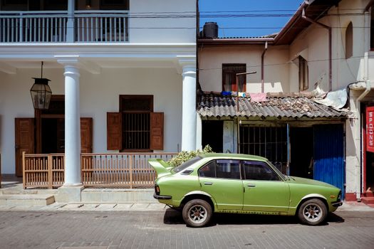 A Green Toyota Corolla Parked Near the Houses