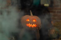 手里拿着一盏发光的南瓜灯，周围环绕着怪异的烟雾，非常适合万圣节