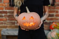 一位有纹身的女子在乡村户外手持一盏发光的南瓜灯，非常适合作为万圣节主题的图片